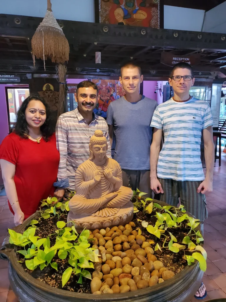 Gäste der Klinik bei der Buddha-Statue, umgeben von Pflanzen